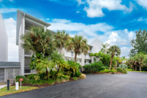 Three story condominium building behind palm trees