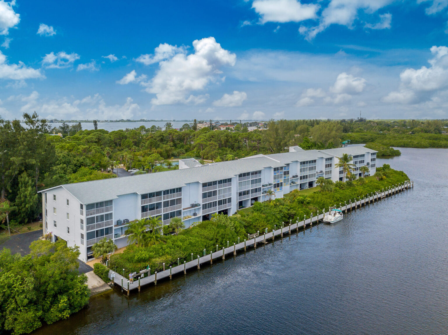 aerial of condominium building by the water and surrounded by trees