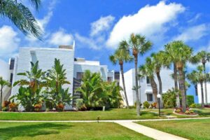 two story condo buildings with pathway and palm trees in foreground