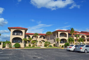 two story condo building with parking lot and palm trees