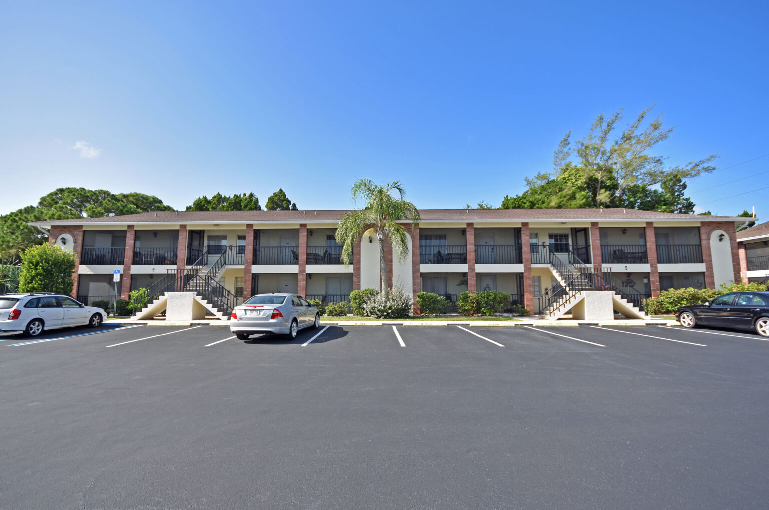 palm manor two story condominium building with cars parked in front of it