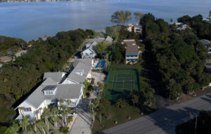 aerial showing Oakwater Cove building and tennis court with bay in the background