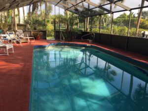 pool under pool cage with a couple recliners